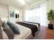 Staged primary bedroom with a rug, potted tree, and balcony access through sliding glass doors at 2935 Lichen Ln # D, Clearwater, FL 33760