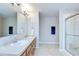 Bright bathroom featuring double sinks with large mirror and a tiled walk-in shower with glass doors at 3012 Magnolia Meadows Dr, Plant City, FL 33567