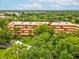Aerial view of condo building with red arrow surrounded by mature trees and green landscaping at 3062 Eastland Blvd # 405, Clearwater, FL 33761
