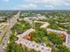 Aerial view of condo building with red arrow, surrounding trees, highway and stores in the background at 3062 Eastland Blvd # 405, Clearwater, FL 33761
