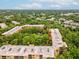 An aerial view of the condo complex surrounded by lush trees on a partly cloudy day at 3062 Eastland Blvd # 405, Clearwater, FL 33761