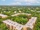 An aerial view of the condo complex surrounded by lush trees and greenery under a partly cloudy sky at 3062 Eastland Blvd # 405, Clearwater, FL 33761