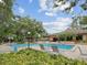 Community pool with lounge chairs, lush landscaping, and a clubhouse in the background at 3062 Eastland Blvd # 405, Clearwater, FL 33761