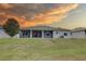 View of the back exterior with a screened-in patio and green lawn at sunset at 3813 Salida Delsol Dr, Ruskin, FL 33573