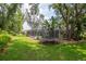 A large backyard with a screened pool and a trampoline, surrounded by trees and greenery at 3821 Turkey Oak Dr, Valrico, FL 33596