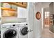 Laundry area with front loading washer and dryer, storage shelves, and access to hallway at 3821 Turkey Oak Dr, Valrico, FL 33596