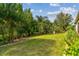 Lush backyard with manicured lawn, mature trees, and a garden with brick borders at 4089 Windcrest Dr, Wesley Chapel, FL 33544