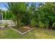 Landscaped backyard with green lawn, mature trees, and a decorative garden area at 4089 Windcrest Dr, Wesley Chapel, FL 33544