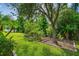 Well-maintained backyard with green lawn, mature trees, and a charming garden space at 4089 Windcrest Dr, Wesley Chapel, FL 33544