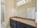 Bathroom featuring granite countertop, dark cabinets, and large mirror at 4089 Windcrest Dr, Wesley Chapel, FL 33544