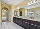 Bright bathroom featuring double vanity with dark cabinets, granite countertops, and walk-in shower at 4089 Windcrest Dr, Wesley Chapel, FL 33544