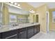 Bright bathroom featuring double vanity with dark cabinets, granite countertops, and walk-in shower at 4089 Windcrest Dr, Wesley Chapel, FL 33544