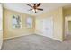 Bedroom featuring neutral carpeting, ceiling fan, closet, and two windows at 4089 Windcrest Dr, Wesley Chapel, FL 33544