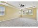 Spacious primary bedroom with tray ceiling, ceiling fan, and large windows at 4089 Windcrest Dr, Wesley Chapel, FL 33544