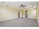 Bedroom with neutral paint and carpet featuring tray ceiling, ceiling fan, and arched doorway at 4089 Windcrest Dr, Wesley Chapel, FL 33544