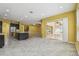 Open living room with island kitchen, tile floors, and sliding doors to an enclosed lanai at 4089 Windcrest Dr, Wesley Chapel, FL 33544