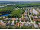 High-angle aerial view of a residential neighborhood with homes, pools, and mature trees, next to a large lake at 4133 Auston Way, Palm Harbor, FL 34685