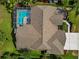 Aerial view of a single-Gathering home with a brown shingle roof, screened pool, and lush green landscaping at 4133 Auston Way, Palm Harbor, FL 34685