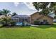 Large backyard with green lawn, tropical plants, and screened-in pool area, perfect for outdoor enjoyment at 4133 Auston Way, Palm Harbor, FL 34685