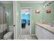 Green bathroom with a tiled floor, toilet, vanity, and view to a blue-themed bedroom at 4133 Auston Way, Palm Harbor, FL 34685