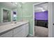 Bright bathroom with a vanity, mirror, and a doorway leading to a purple-themed bedroom at 4133 Auston Way, Palm Harbor, FL 34685