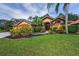 Charming single-story home featuring a landscaped front yard, a double-door entry, and a three-car garage at 4133 Auston Way, Palm Harbor, FL 34685