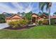Charming single-story home featuring a landscaped front yard, a double-door entry, and a three-car garage at 4133 Auston Way, Palm Harbor, FL 34685