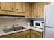Well-lit kitchen featuring wood cabinetry, a double basin sink, and standard appliances at 4324 Tahitian Gardens Cir # J, Holiday, FL 34691
