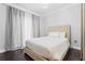 Bright bedroom featuring a queen bed, woven headboard, dark hardwood floors and decorative curtains at 512 1St St # 108, Indian Rocks Beach, FL 33785