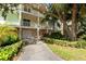 Three-story home featuring multiple balconies, a ground-level garage, and lush tropical landscaping at 512 1St St # 108, Indian Rocks Beach, FL 33785