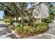 Exterior of the property with mature trees and lush landscaping, including a golf cart at 512 1St St # 108, Indian Rocks Beach, FL 33785