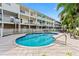 Community swimming pool surrounded by lounge seating and condo building on a bright sunny day at 512 1St St # 108, Indian Rocks Beach, FL 33785