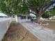 Quaint home showcasing a well-kept lawn, mature tree, and a white picket fence enhancing the property's perimeter at 5175 88Th N Ave, Pinellas Park, FL 33782