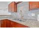 Close-up of a kitchen sink, featuring a granite countertop, tile backsplash, and dark wood cabinets at 5326 22Nd N Ave, St Petersburg, FL 33710