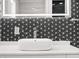 Close-up on modern bathroom sink with a unique patterned backsplash and contemporary faucet at 600 115Th Ave, Treasure Island, FL 33706