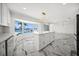 Modern kitchen boasts white cabinets, an island, and sleek appliances with backyard views at 600 115Th Ave, Treasure Island, FL 33706