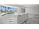 Modern kitchen boasts white cabinets, an island, and marble floors with views of the outdoor pool and dock at 600 115Th Ave, Treasure Island, FL 33706