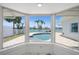 Interior view of bay windows overlooking pool and water with white fence and palms at 600 115Th Ave, Treasure Island, FL 33706