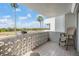 Spacious balcony featuring a unique block wall, comfortable seating, and a view of lush tropical landscaping at 7 Elgin Pl # 202, Dunedin, FL 34698