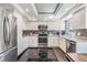 Well-lit kitchen featuring white cabinets, black splash-back and granite countertops with stainless steel appliances at 7 Elgin Pl # 202, Dunedin, FL 34698