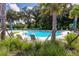 Community pool featuring turquoise water surrounded by lush greenery, palm trees and comfortable lounge chairs at 7034 Emerald Spring Loop, New Port Richey, FL 34653
