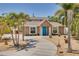 Charming home with a blue front door, stone accents, landscaped yard, and a curved driveway with palm trees at 941 65Th S St, St Petersburg, FL 33707