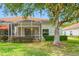 Backyard featuring a screened-in lanai and mature trees, providing shade to the outdoor living area at 10255 Devonshire Lake Dr, Tampa, FL 33647