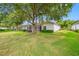 A view of the backyard featuring a lush lawn, a screened-in lanai, and mature trees providing shade at 10255 Devonshire Lake Dr, Tampa, FL 33647