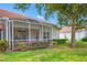 Backyard featuring a screened-in lanai, mature trees, and green landscaping offering shade and privacy at 10255 Devonshire Lake Dr, Tampa, FL 33647