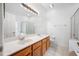 Bathroom with double sink, quartz countertop, vanity, and a tiled shower behind glass doors at 10255 Devonshire Lake Dr, Tampa, FL 33647