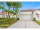 Charming home featuring a white exterior, red tile roof, palm trees, and a two-car garage at 10255 Devonshire Lake Dr, Tampa, FL 33647
