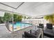Backyard pool with covered patio and lounge seating, surrounded by lush tropical landscaping and privacy fence at 11110 105Th Ave, Largo, FL 33778