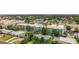 Aerial view of a light blue multi-unit building with a pool, parking, mature trees, and surrounding homes at 11447 Park Blvd # 205, Seminole, FL 33772