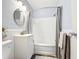 Bright bathroom with white tiled bathtub, shower with gray curtain, white vanity, modern fixtures, and round mirror at 11447 Park Blvd # 205, Seminole, FL 33772